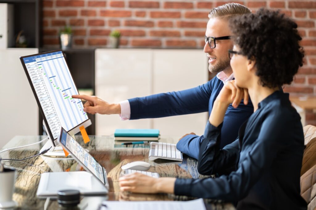 Man and woman analyzing a gantt chart on a computer screen