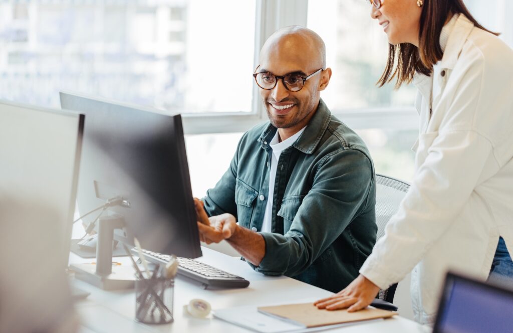 Software engineers using a computer and having a discussion in an office.